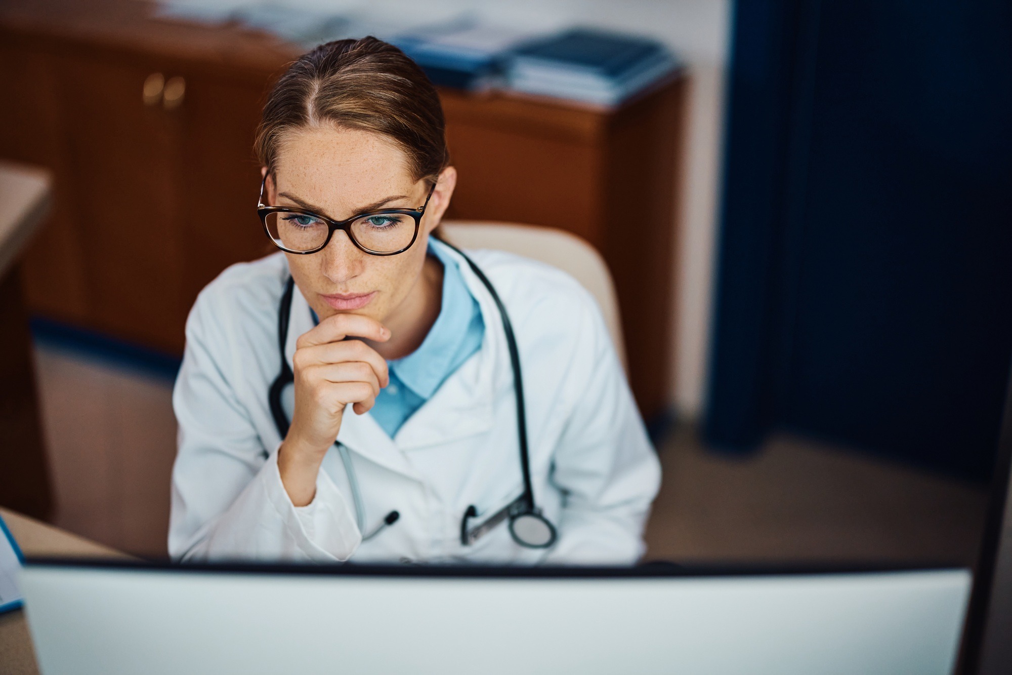 Pensive doctor working on a computer in her office.